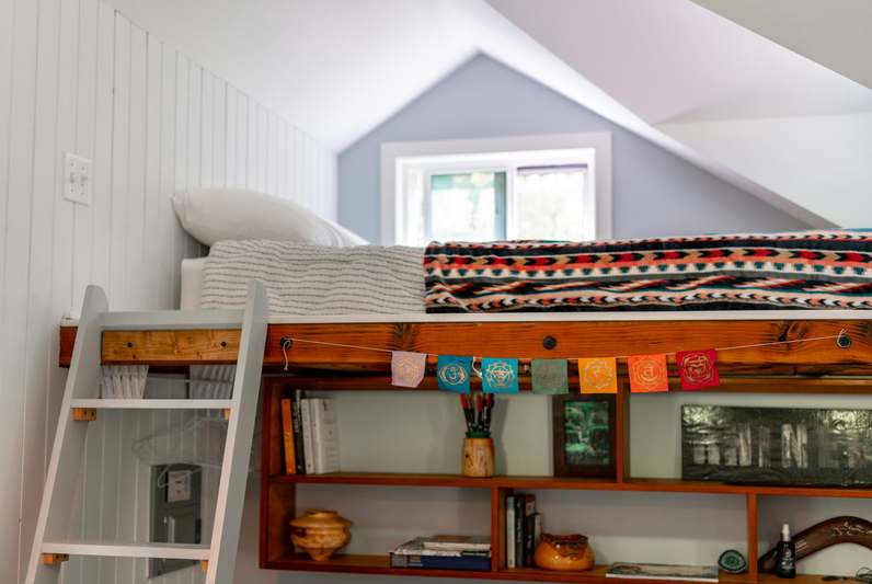 Cozy bedroom featuring a white metal loft bed with integrated workspace and string lights